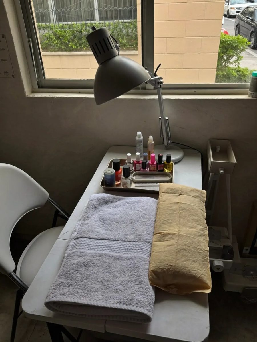 A manicure table and client chair by the window with a tray of files and polishes.
