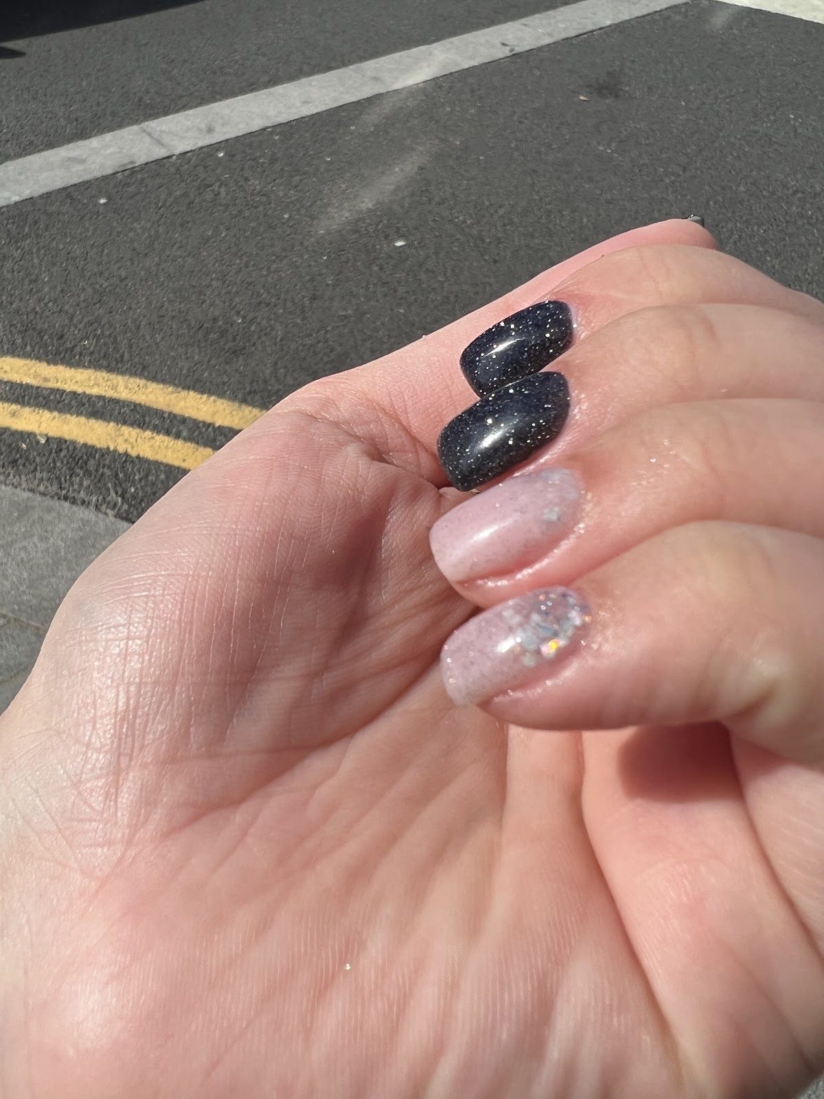 Curled hand showing black glitter and nude glitter nails.